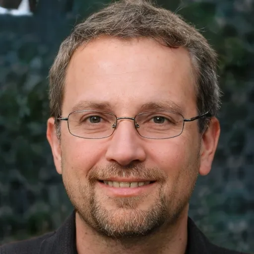 Smiling man with glasses and beard outdoors